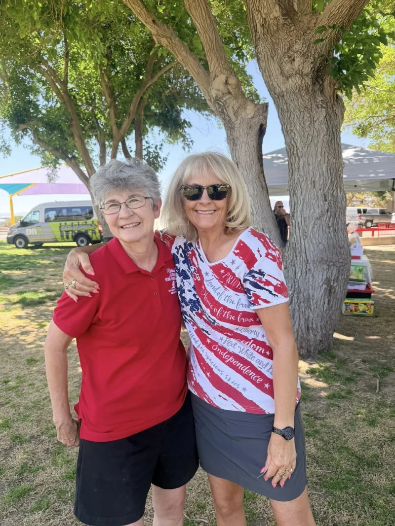 Two women Veterans stand together at an outdoor Chapter 12 event with the DAV transportation van visible in the background.