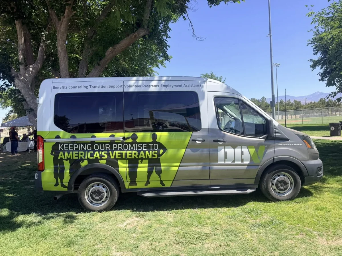 DAV transportation van that gives Nevada Veterans free rides to VA medical appointments, wrapped in Nightvision Green livery reading 'Keeping Our Promise to America's Veterans,' parked under a tree.