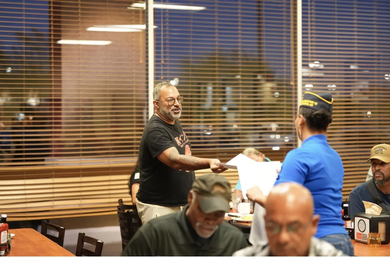 A member hands paperwork across the table as the meeting gets underway.