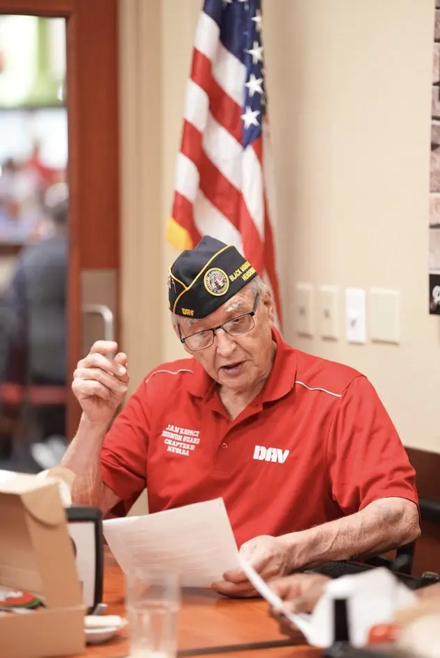 Jan Kopacz reads from a sheet of paper beside the American flag.