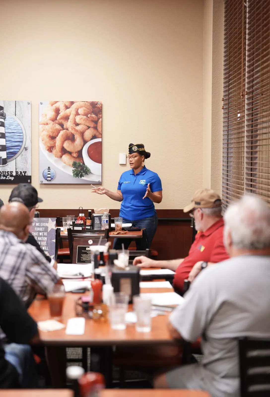 A Chapter officer in a garrison cap addresses the room from the front.