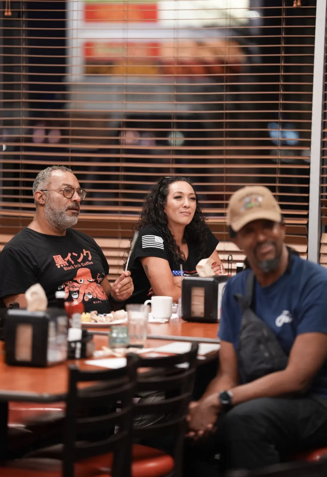 Three members smile together at a table during the meeting.