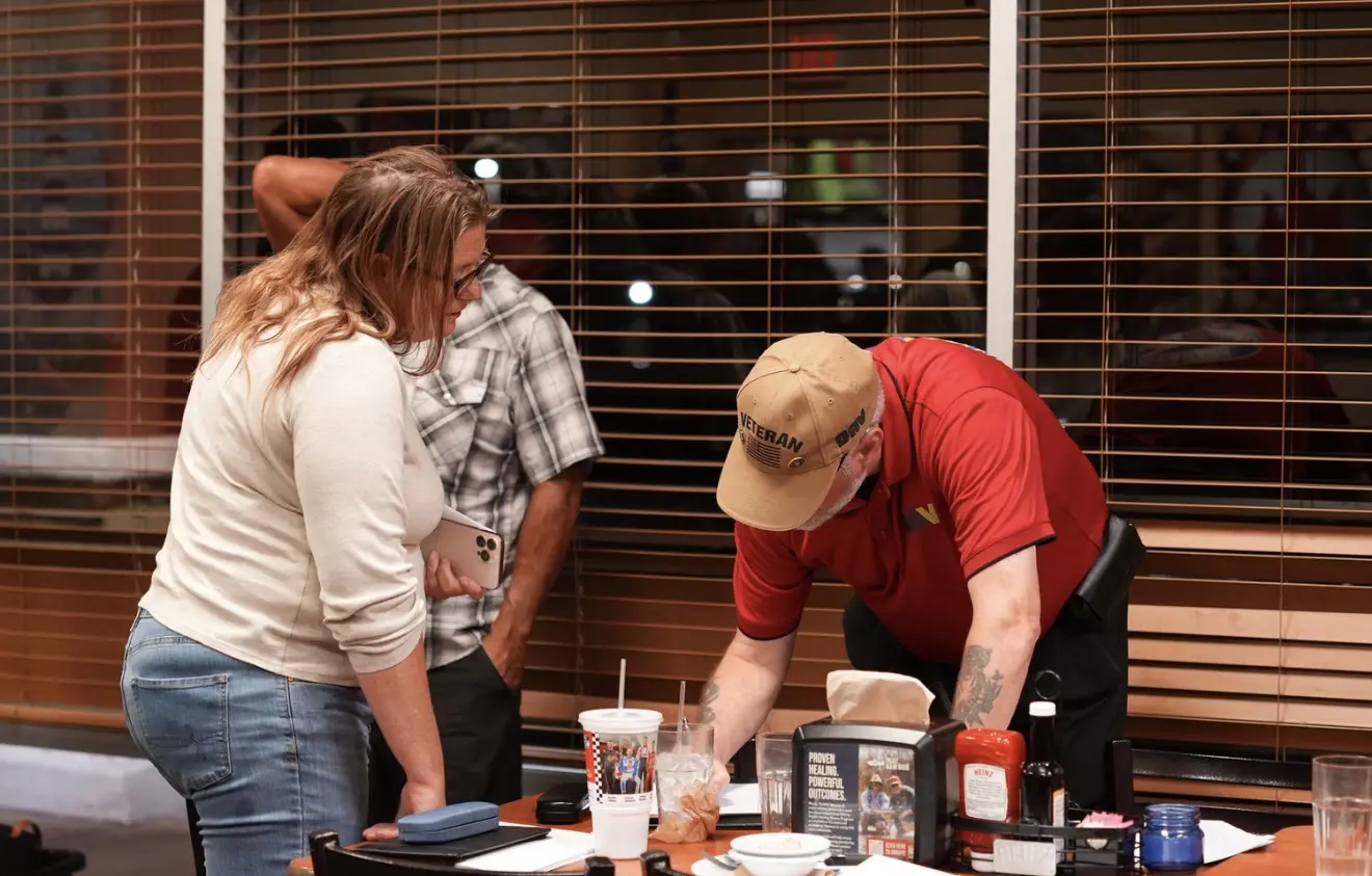 Members help one another with paperwork at a table.