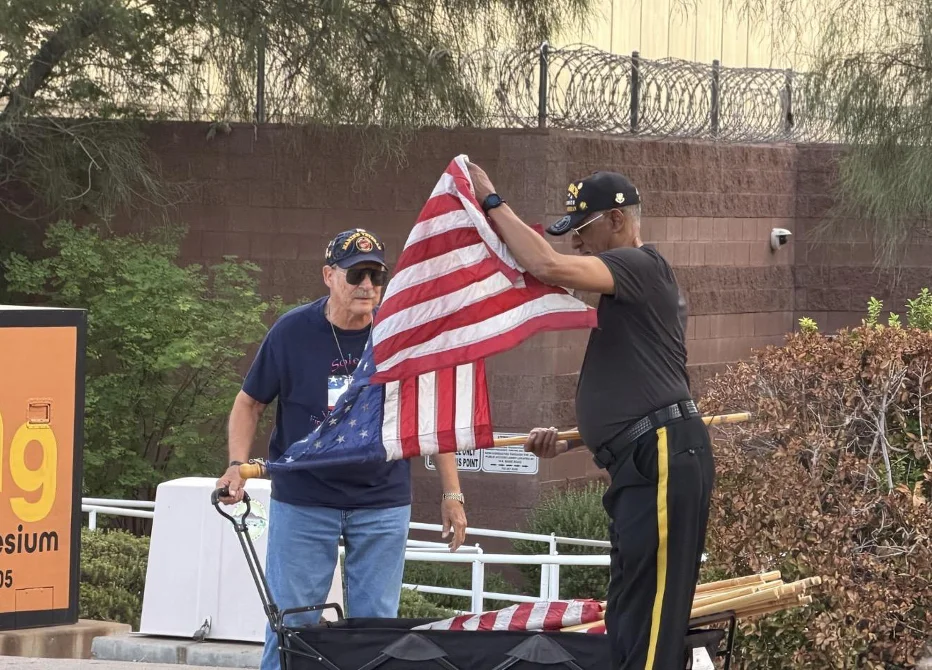 Two Honor Guard members in DAV caps take an American flag off its pole beside a wagon on Water Street.